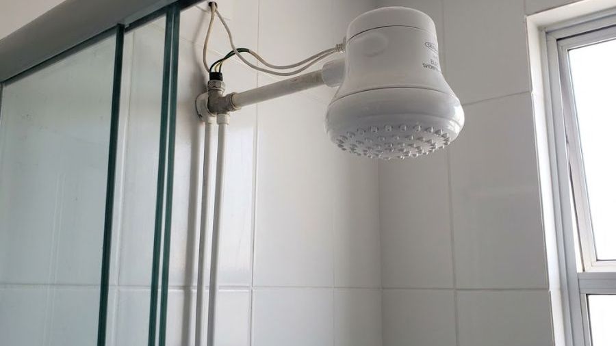 Chuveiro elétrico branco instalado em box de banheiro